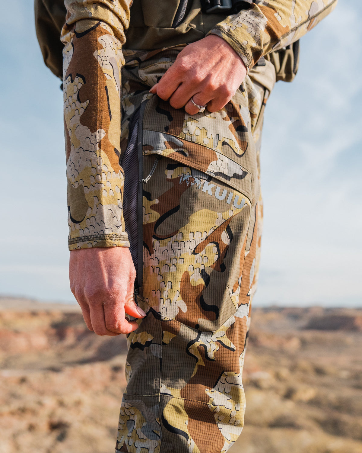 Woman unzipping the hip vent of the Women's Tiburon Pant in Valo Camouflage