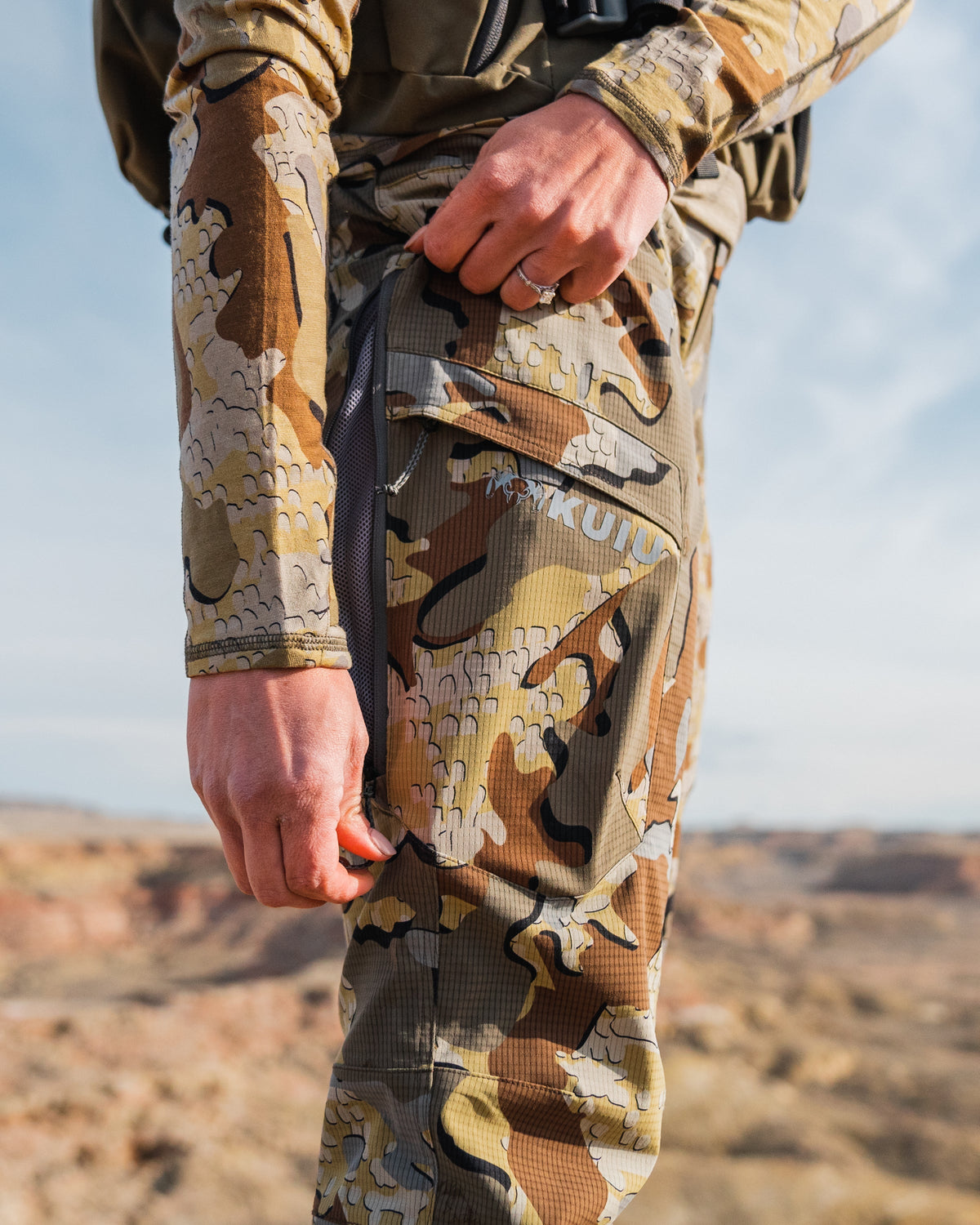 Woman unzipping the hip vent of the Women's Tiburon Pant in Valo Camouflage