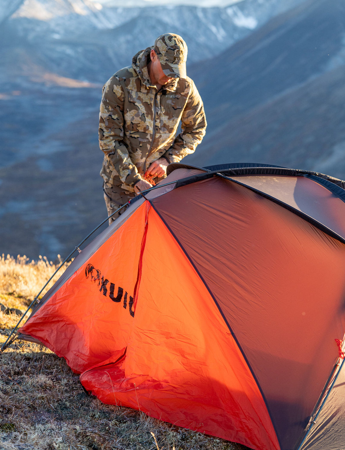 Hunter setting up and securing poles on the Mountain Star 2 Person Tent in Gunmetal Grey, Orange