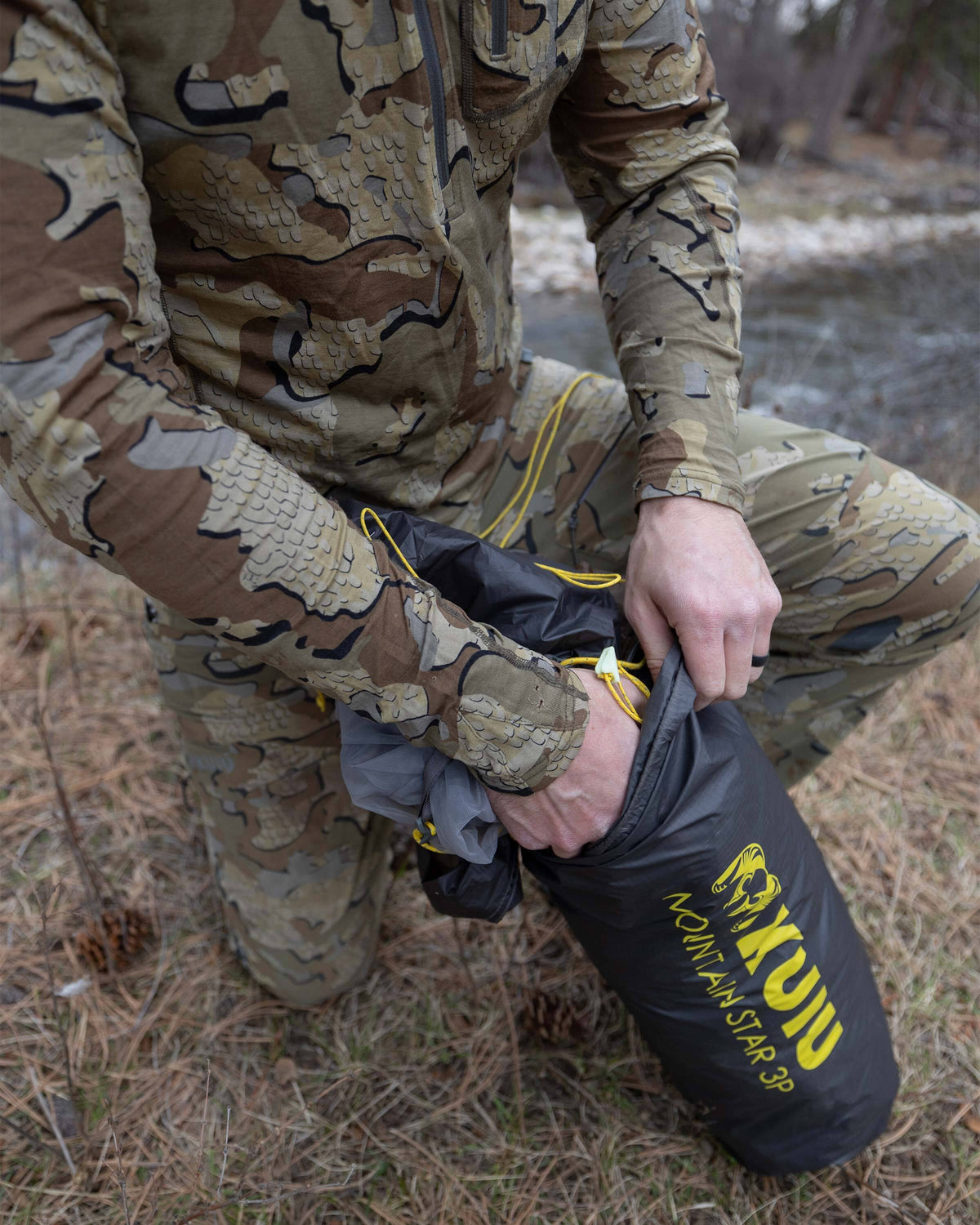 Detailed close up of hunter removing the gunmetal grey Mountain Star 3 Person Tent Footprint from his stuff sack