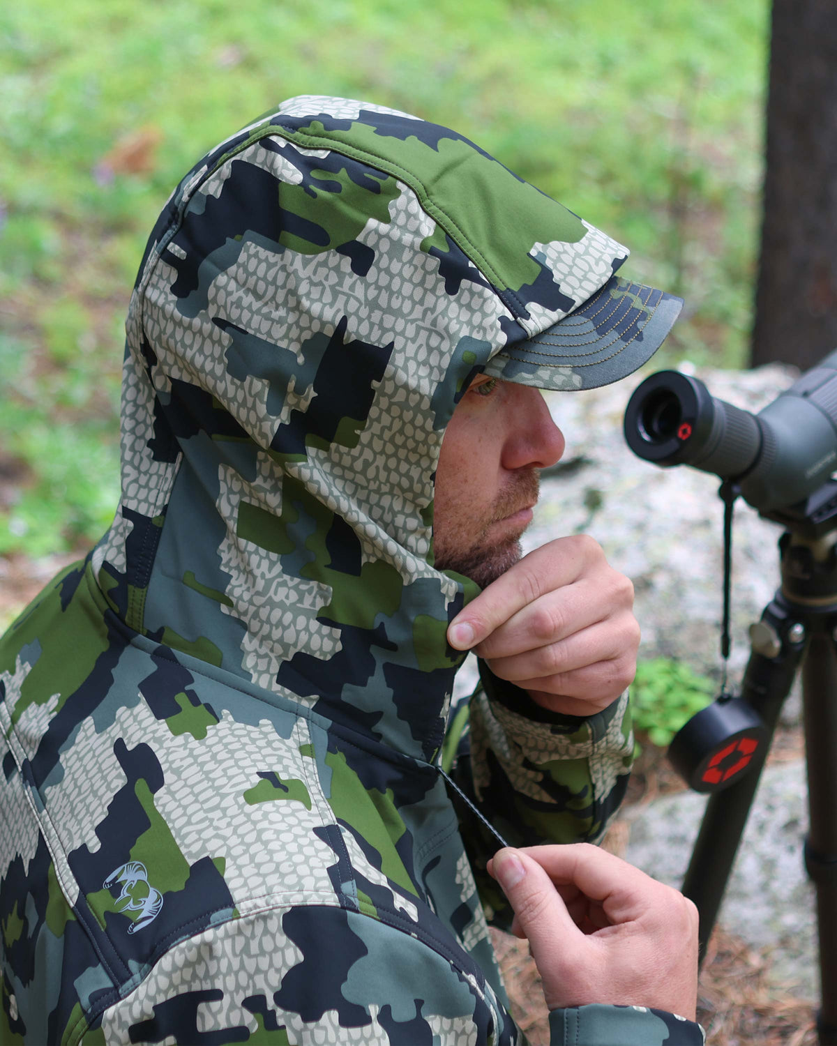 Hunter showcasing back cord-lock adjustable hood with lightly structured visor on the Alpine Hooded Jacket in Verde Camouflage