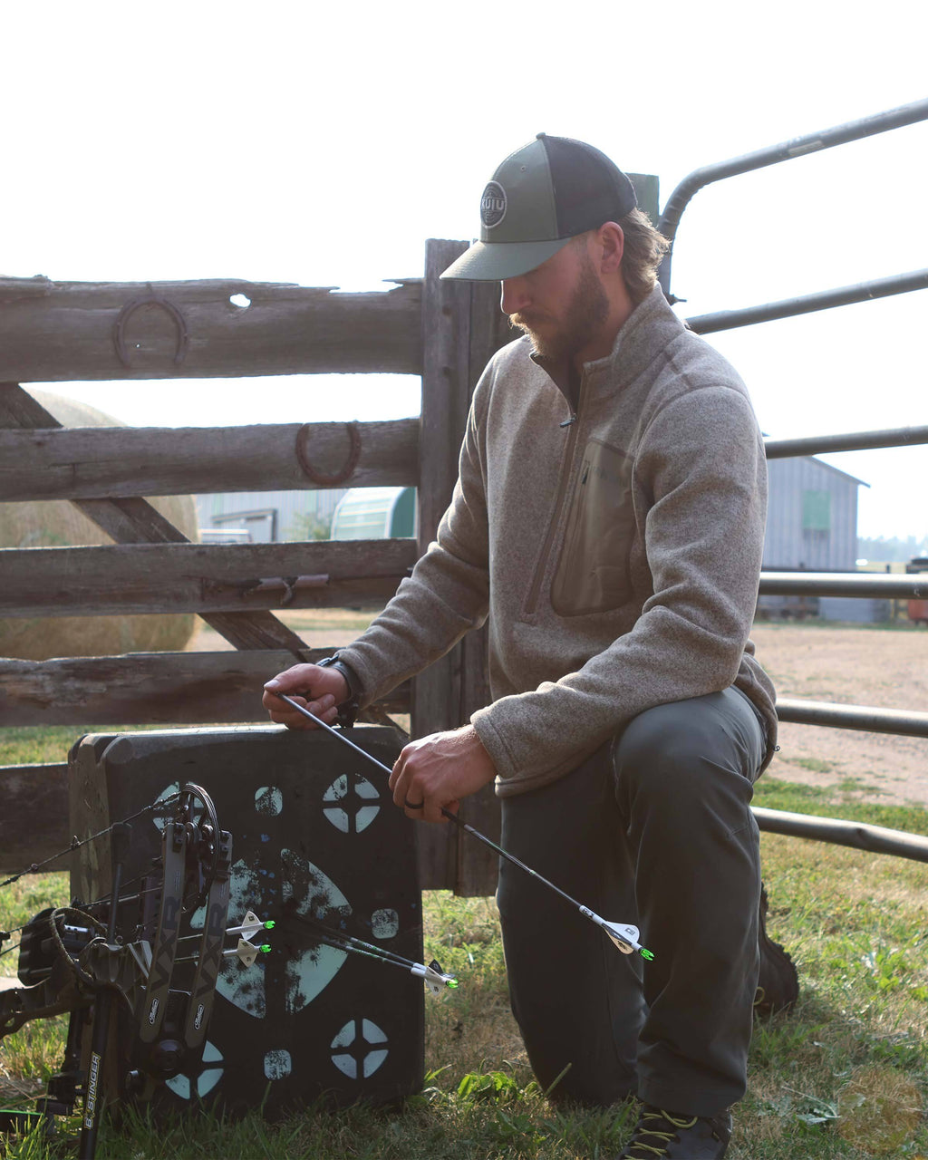 Archer retrieving arrows form archery target, wearing Base Camp Pullover Sweater in Khaki Heather