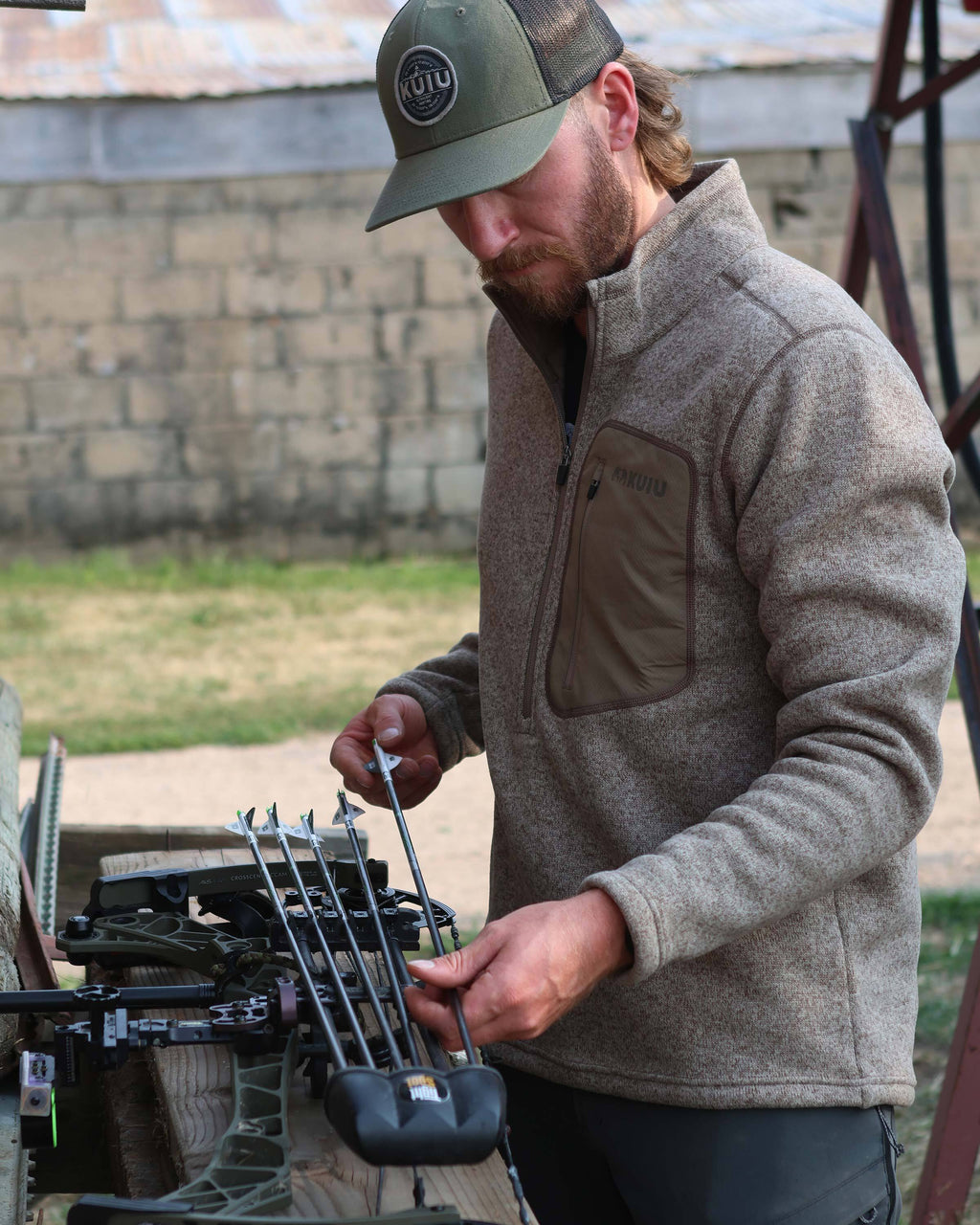 Archer loading his quiver, wearing Base Camp Pullover Sweater in Khaki Heather