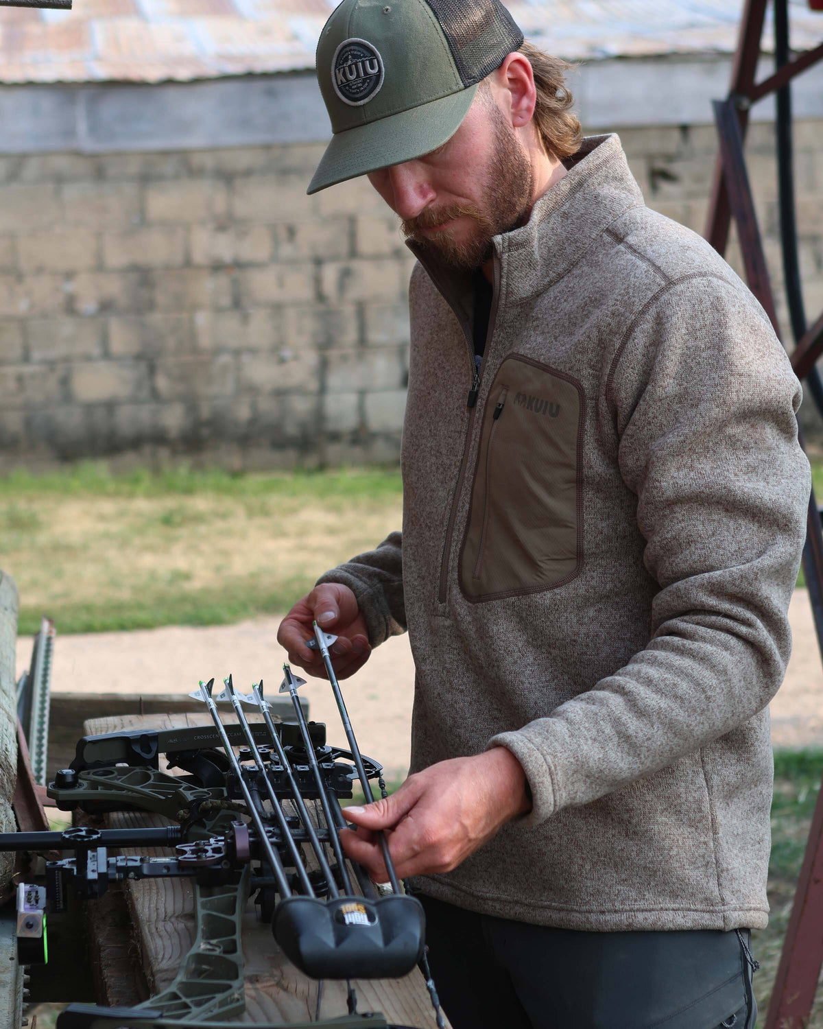 Archer loading his quiver, wearing Base Camp Pullover Sweater in Khaki Heather