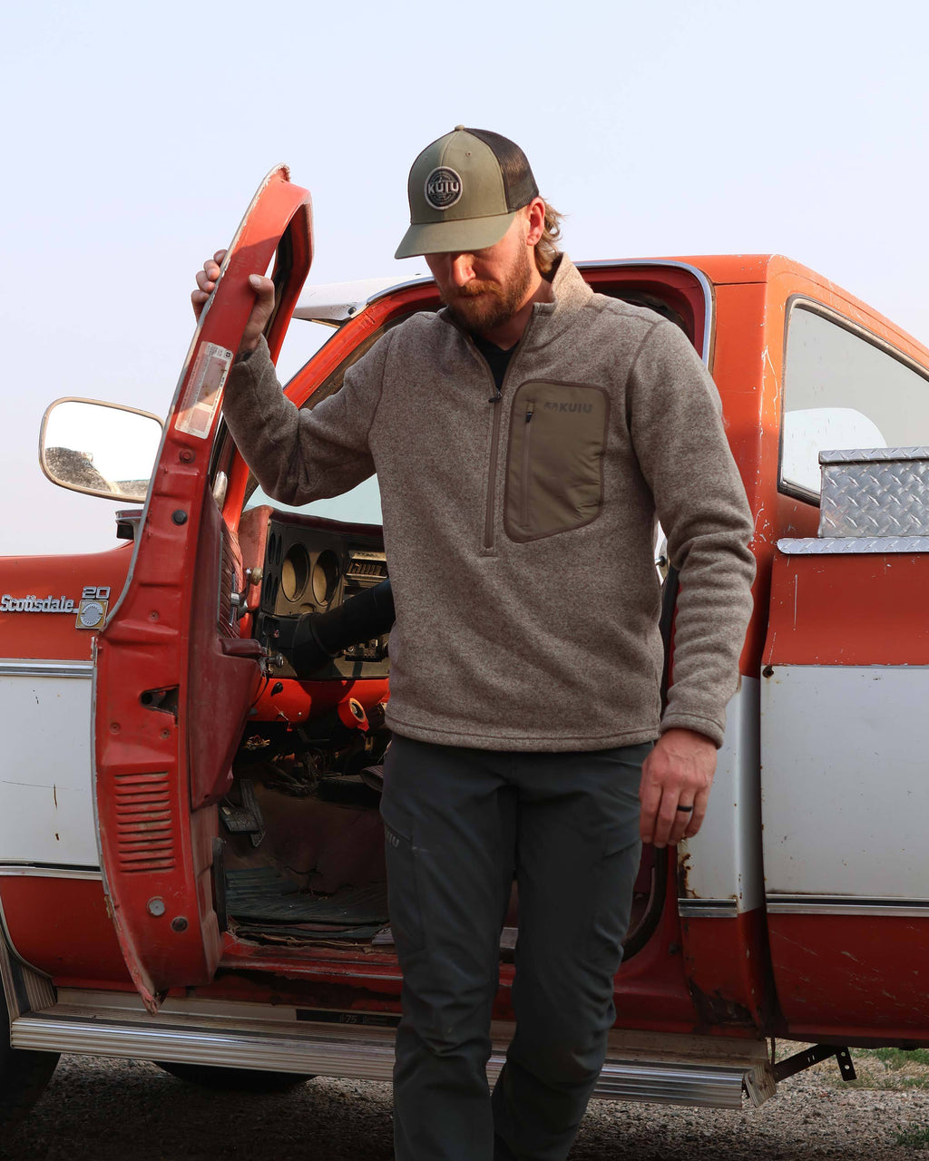 Man stepping out of his truck, wearing Base Camp Pullover Sweater in Khaki Heather