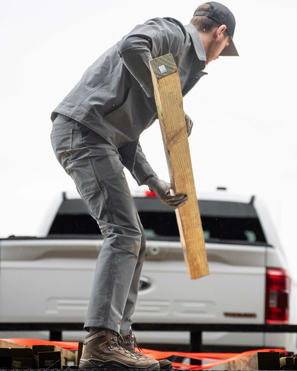 Man loading wood stud in his truck, wearing Brawley Pant in Gunmetal Grey