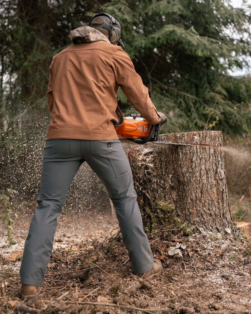 Man chainsawing a tree trunk, highlighting back of Brawley Pant in Gunmetal Grey