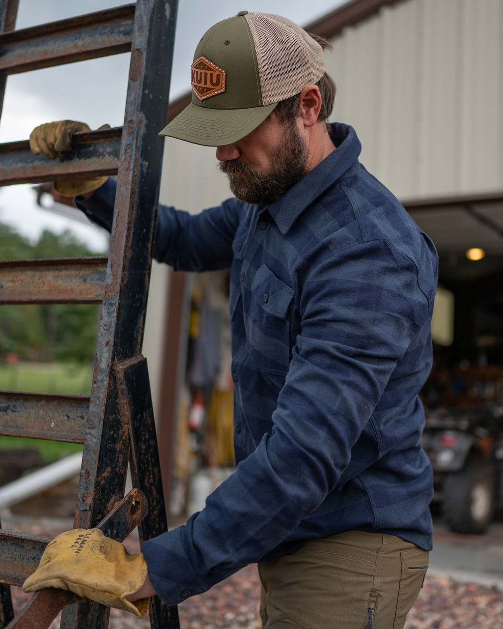 Man lifting trailer grate wearing Field Flannel Shirt in Steel Blue Buffalo Check