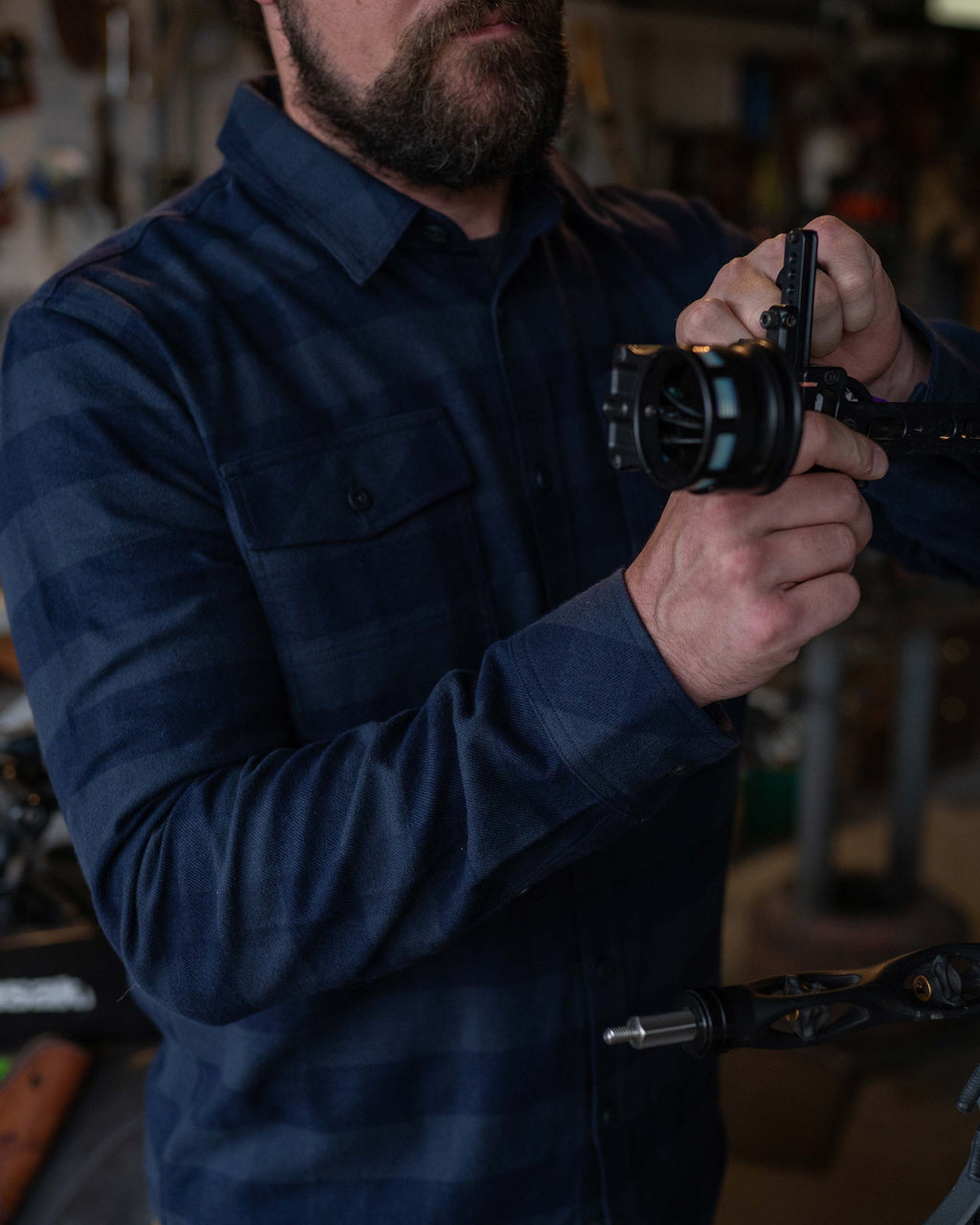 Man tuning compound bow wearing Field Flannel Shirt in Steel Blue Buffalo Check