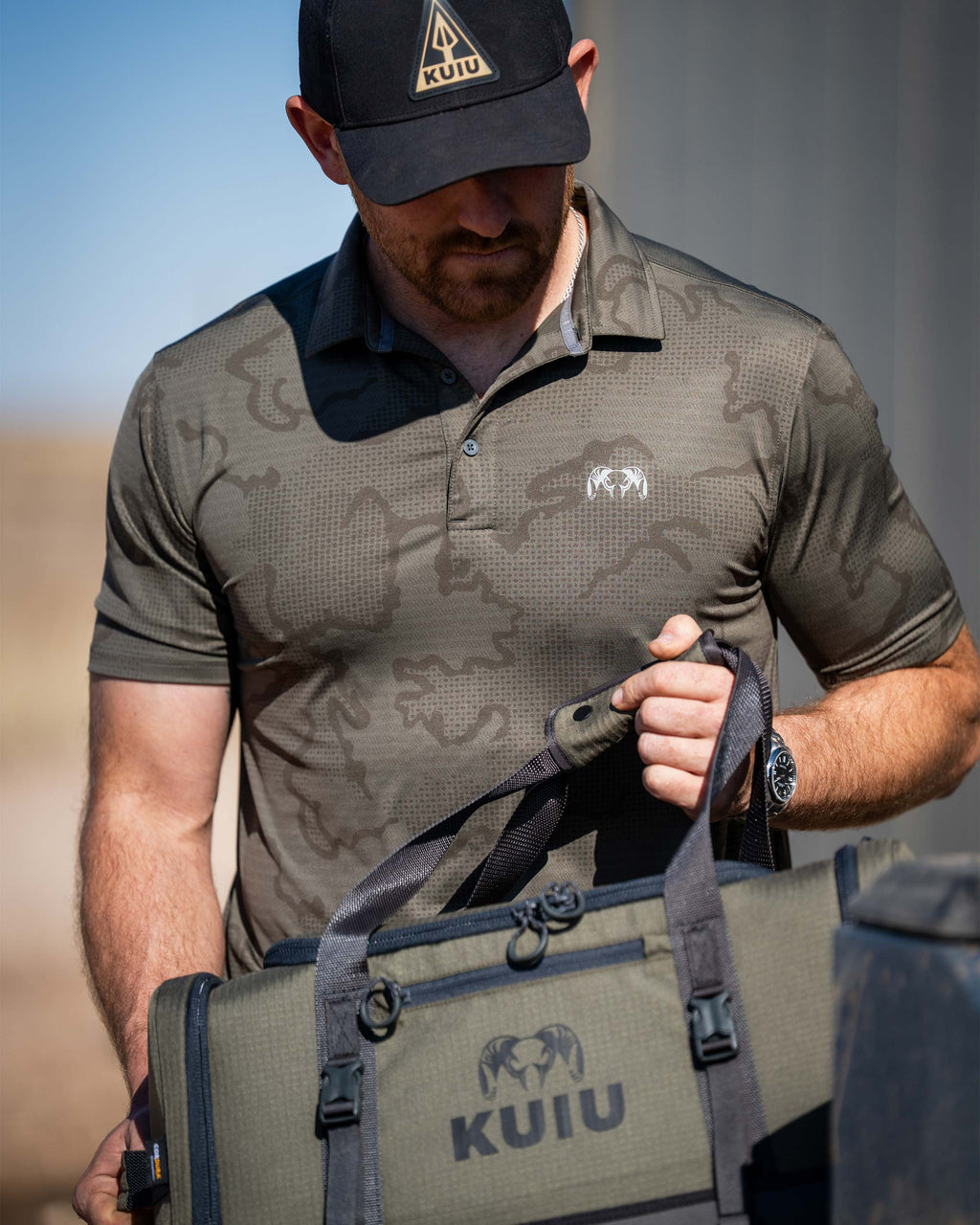 Man carrying KUIU Distance Duffel Bag while wearing KUIU Performance Polo in Ash Brown Tonal.