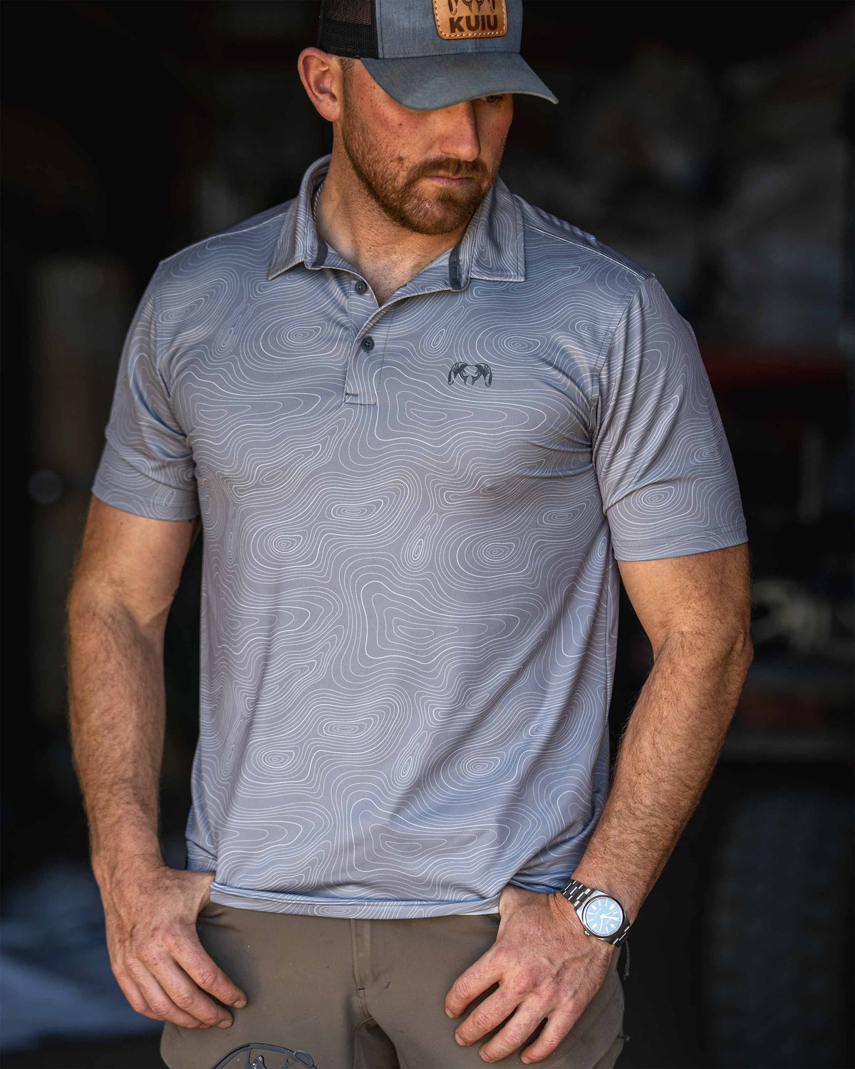 Man stands casually with thumbs resting in his pockets while wearing KUIU Performance Polo in Dark Lunar Grey Topo.