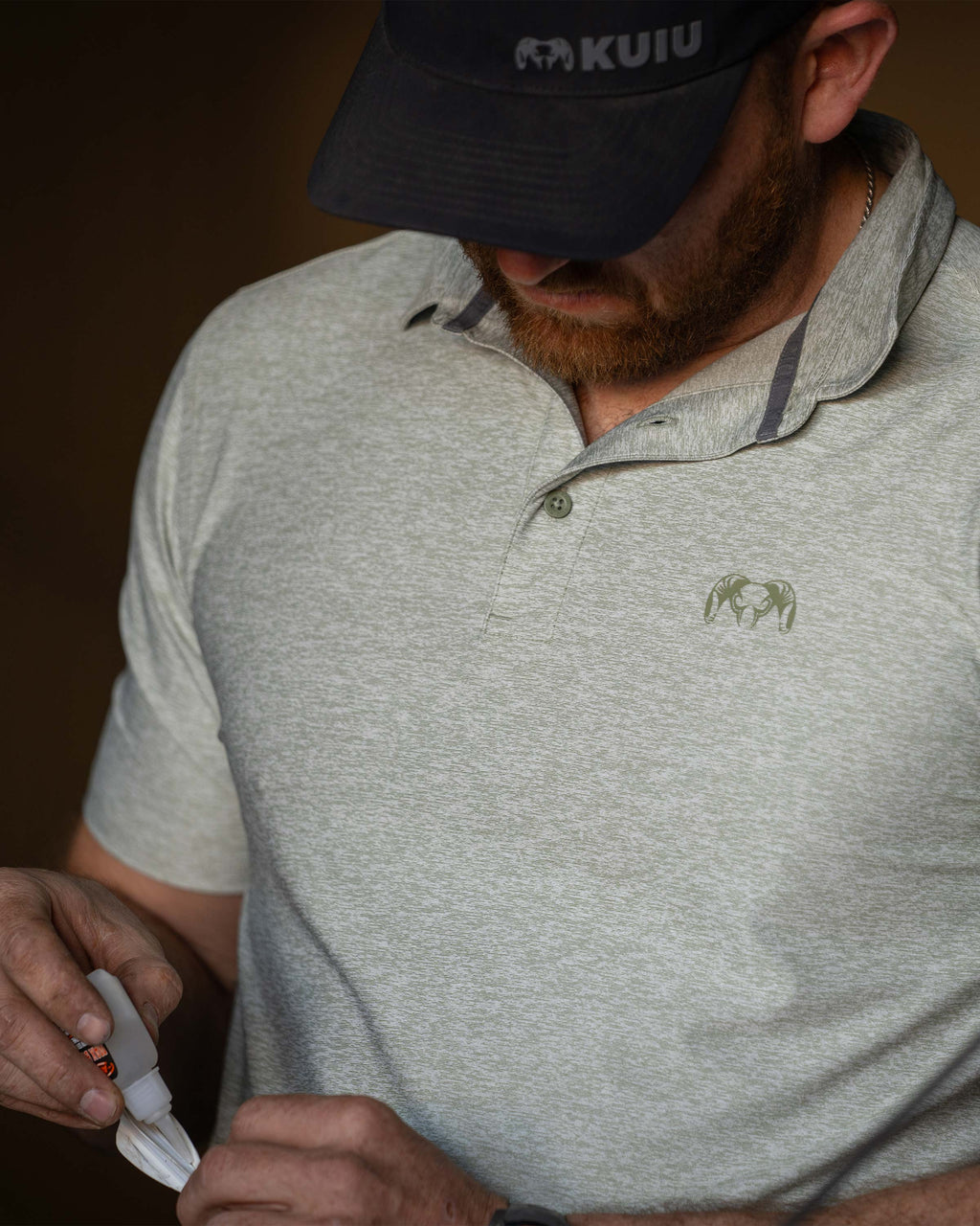 Close-up of Hunter gluing the fletching on his arrow, wearing KUIU Performance Polo T-Shirt in Heather Buckbrush