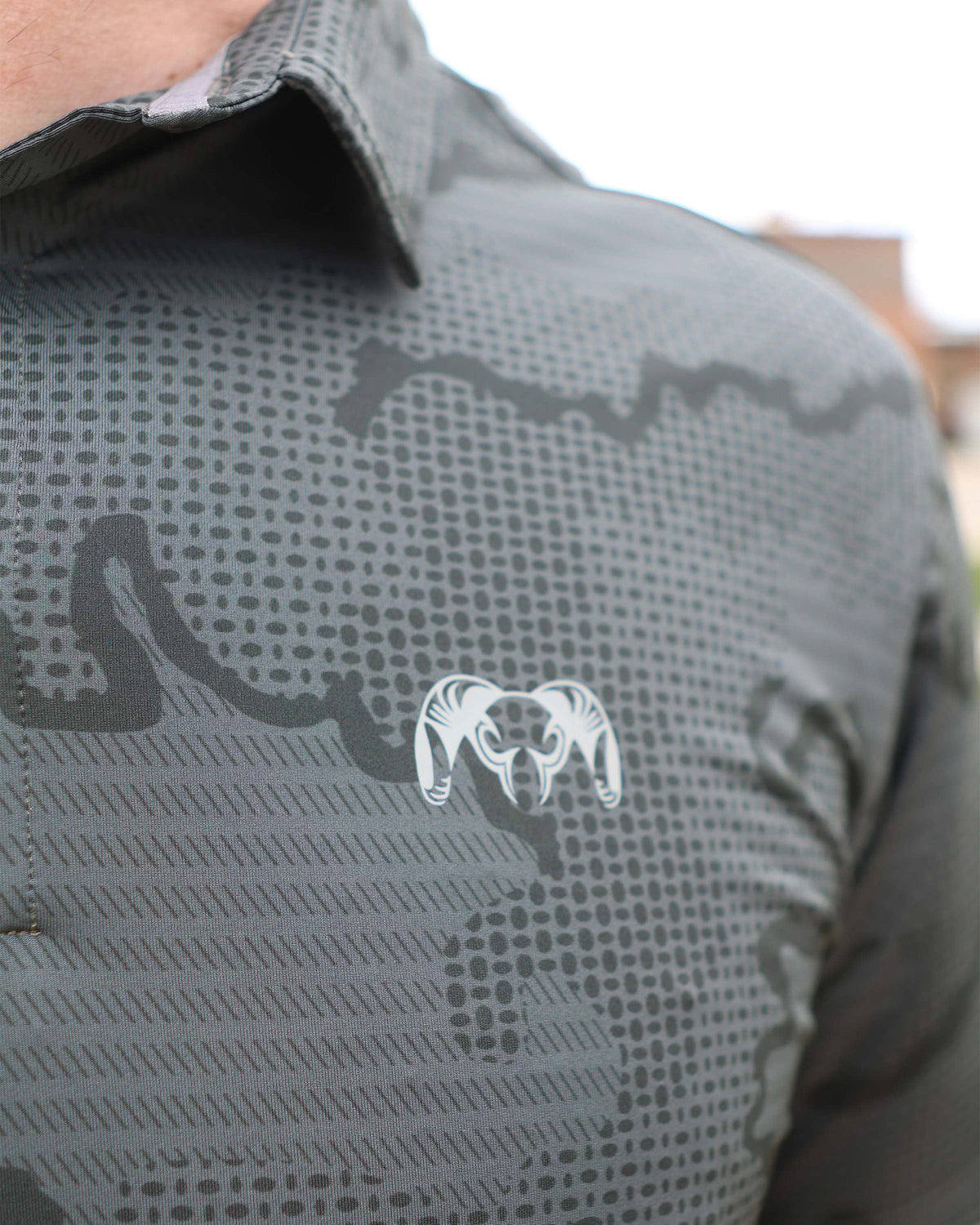 Close-up view of white printed KUIU logo on the left chest of KUIU Performance Polo T-Shirt in Gunmetal Grey Tonal Print