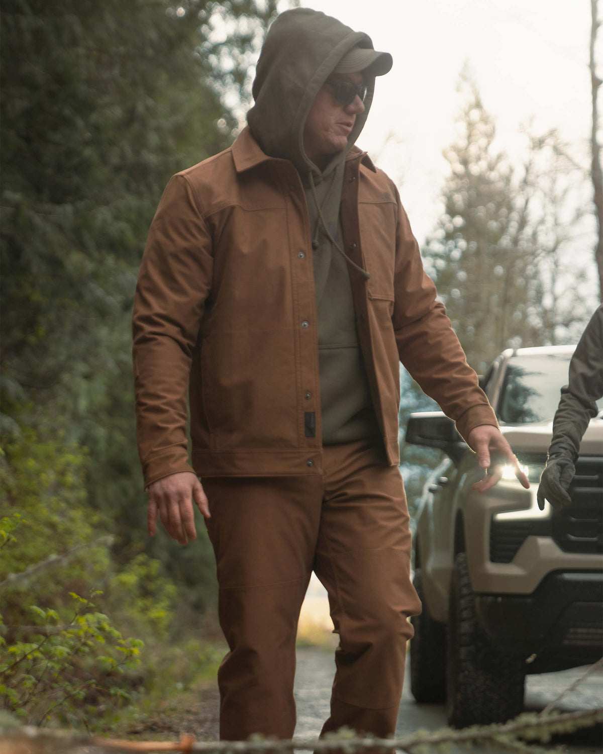 Man in an outdoor setting wearing Brawley Canvas Jacket in Saddle Brown