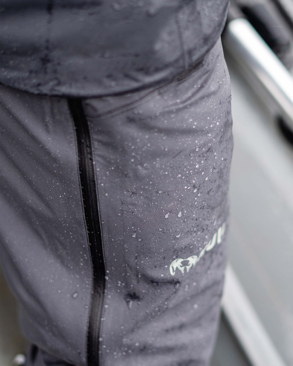 Close-up of water droplets on the Northridge Rain Pant in Gunmetal Grey, Highlighting the waterproof material and full-length side zipper