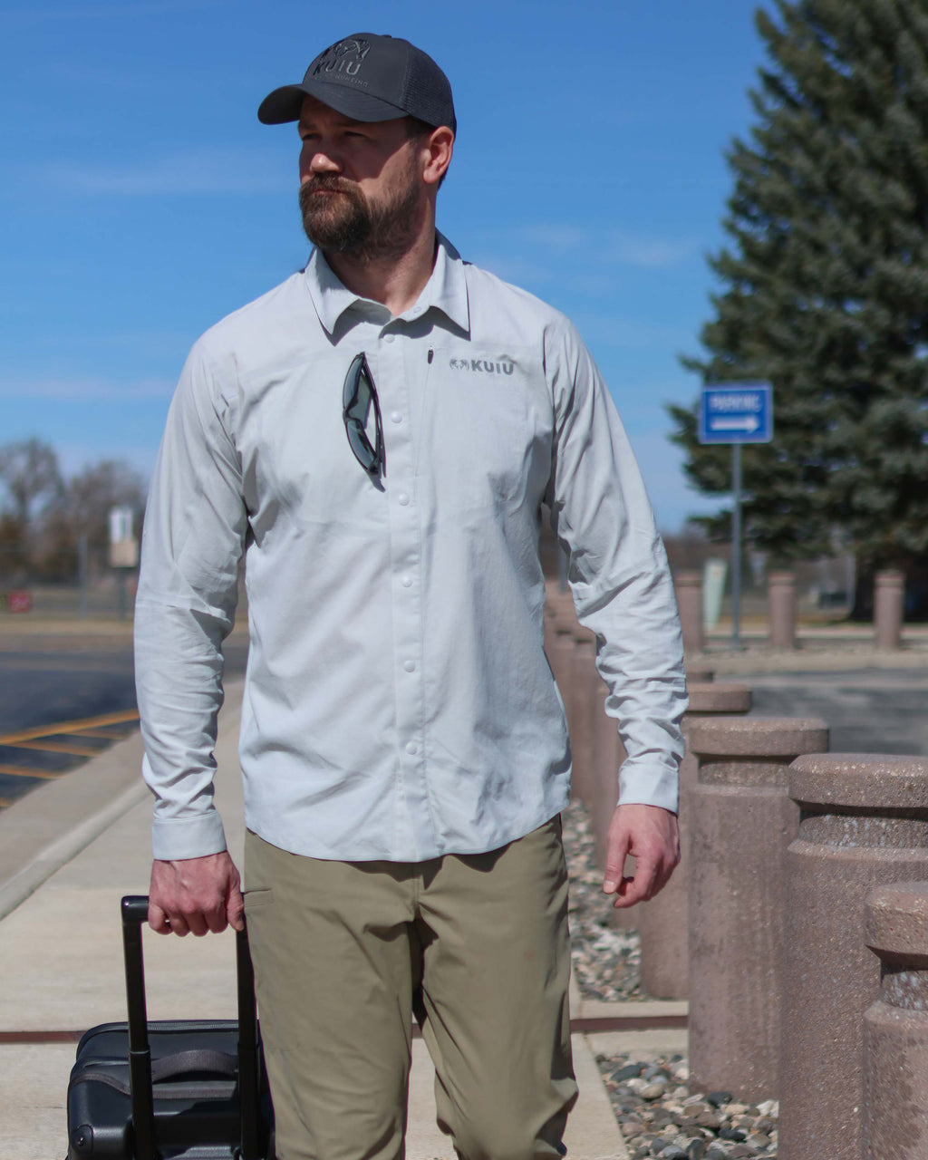 Man strolling on the sidewalk with his Waypoint Roller Bag, wearing Salton Long Sleeve Shirt in Lunar Grey