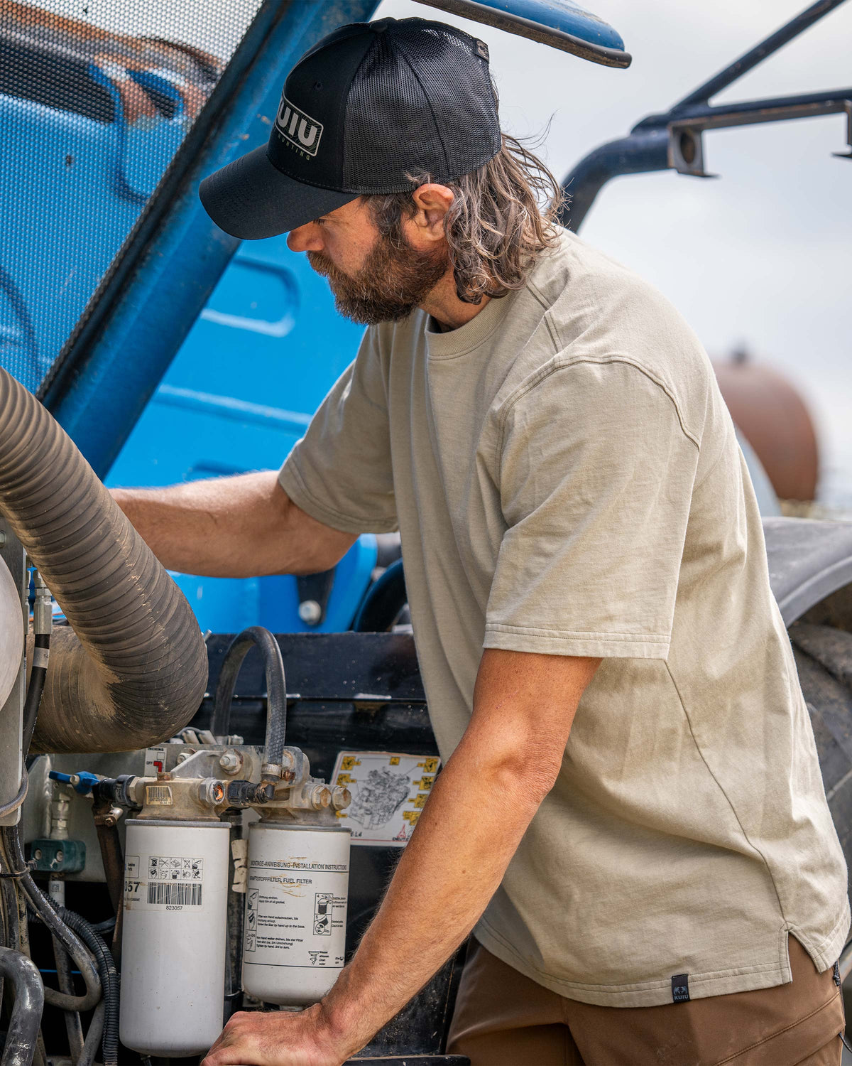 Man working on a farm equipment wearing Workgrade Short Sleeve in Bone Khaki