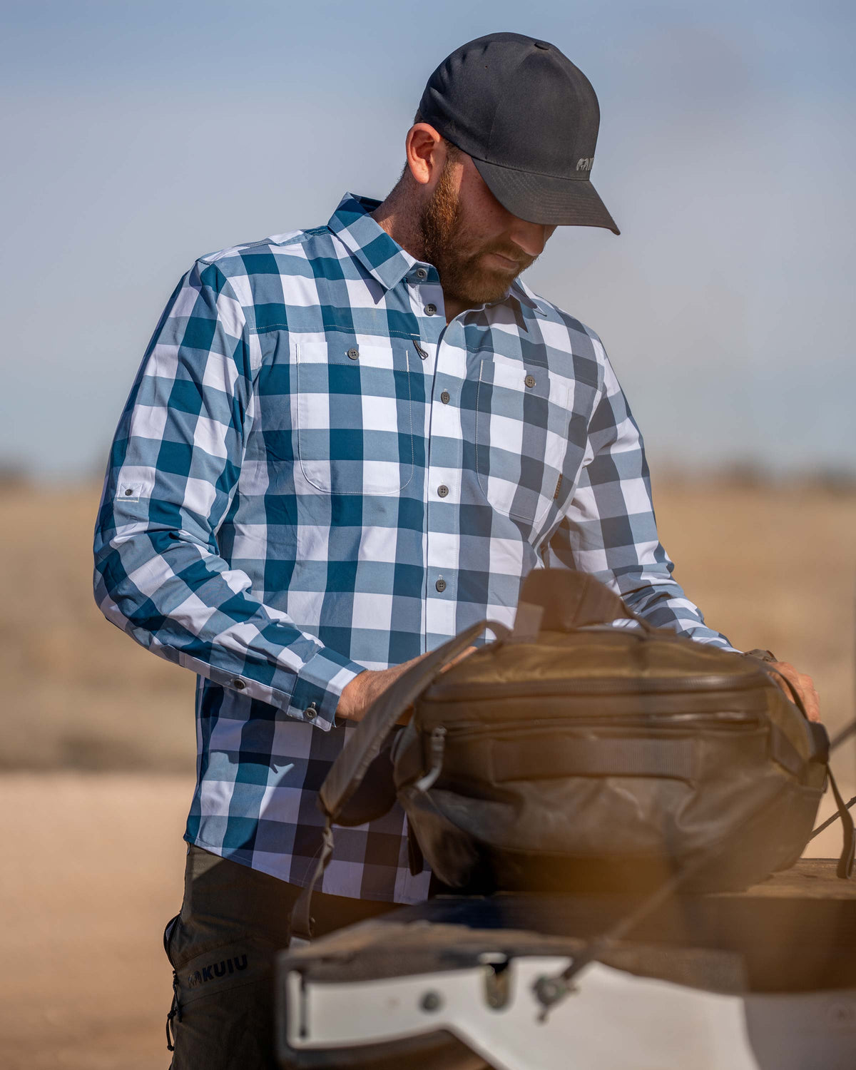 Hunter wearing Borrego LS Shirt in Blue Lake Plaid, looking into his duffel bag