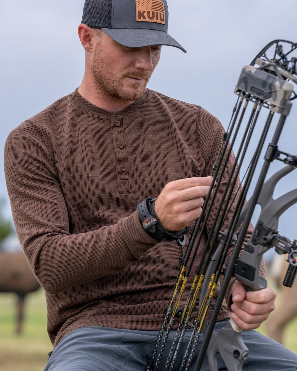 Hunter adjusting his bow wearing Canyon Waffle Henley Shirt in Cedar Heather Brown