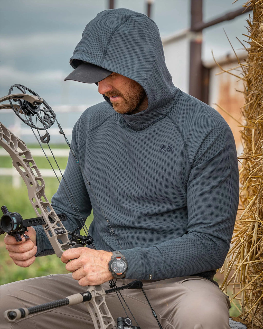 Man adjusting the stabilizer on his bow wearing Canyon Waffle Hoodie in Steel Blue