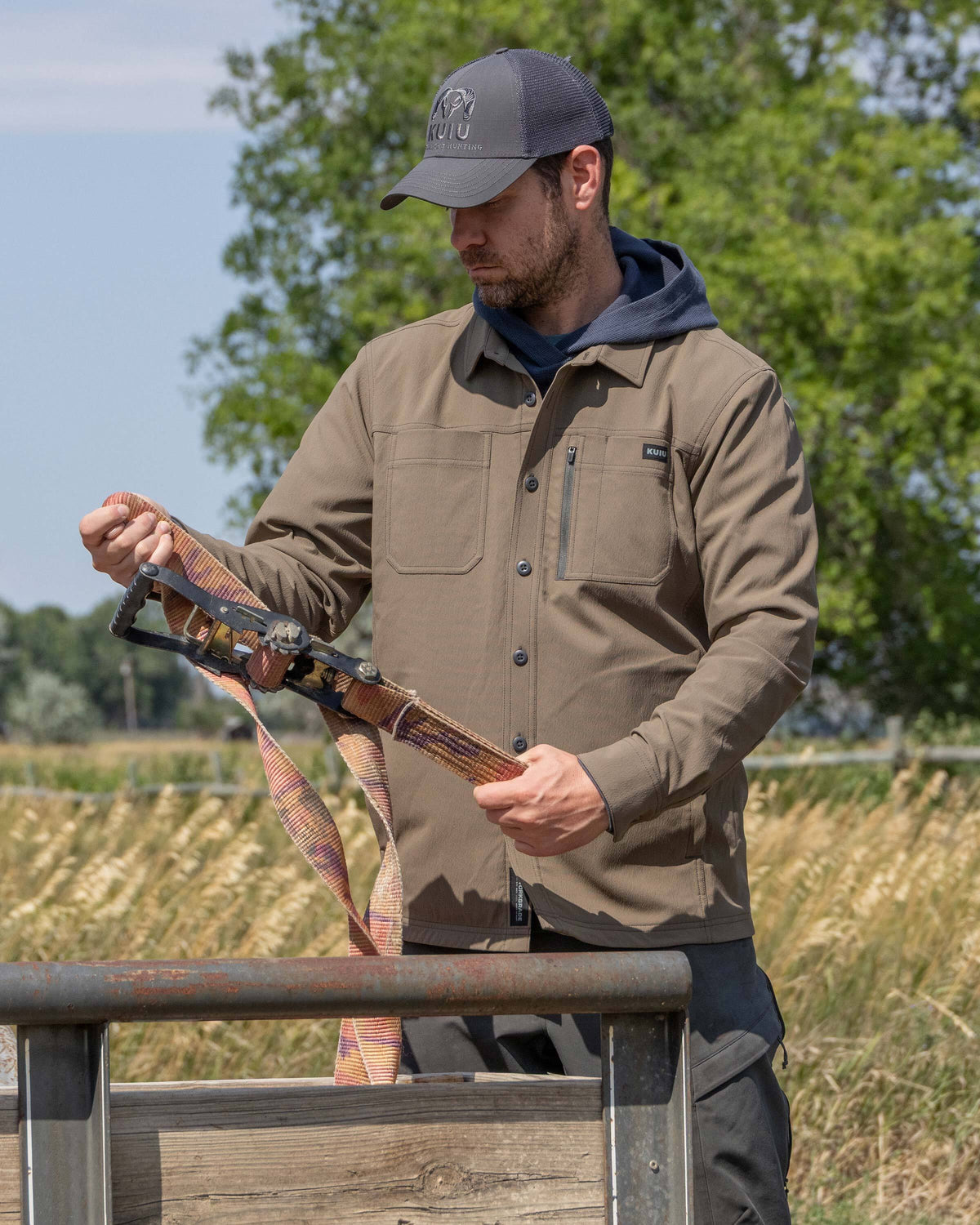 Man holding ratchet straps wearing Motive Flannel Lined Shirt Jacket in Major Brown