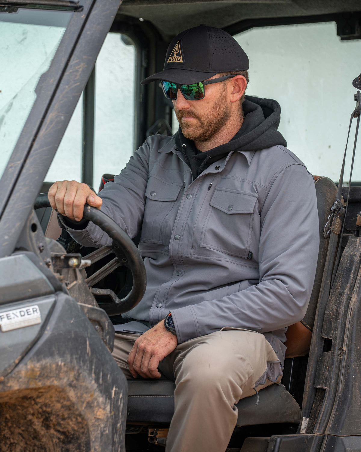 Man sitting in a UTV wearing Tour Shirt Jacket in Castle Rock Grey