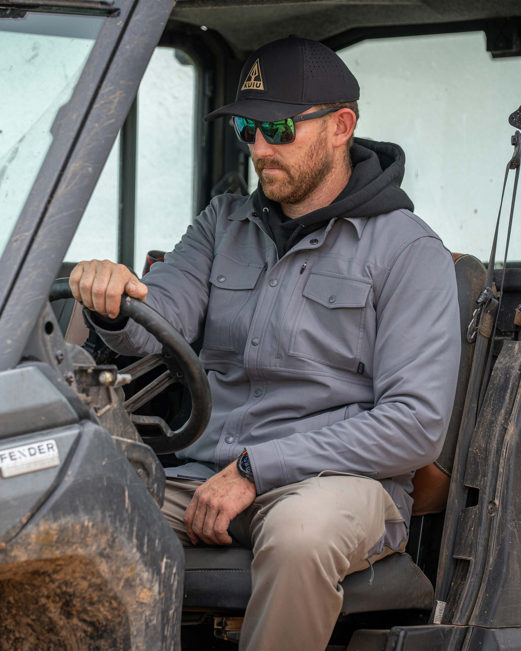 Man sitting in a UTV wearing Tour Shirt Jacket in Castle Rock Grey