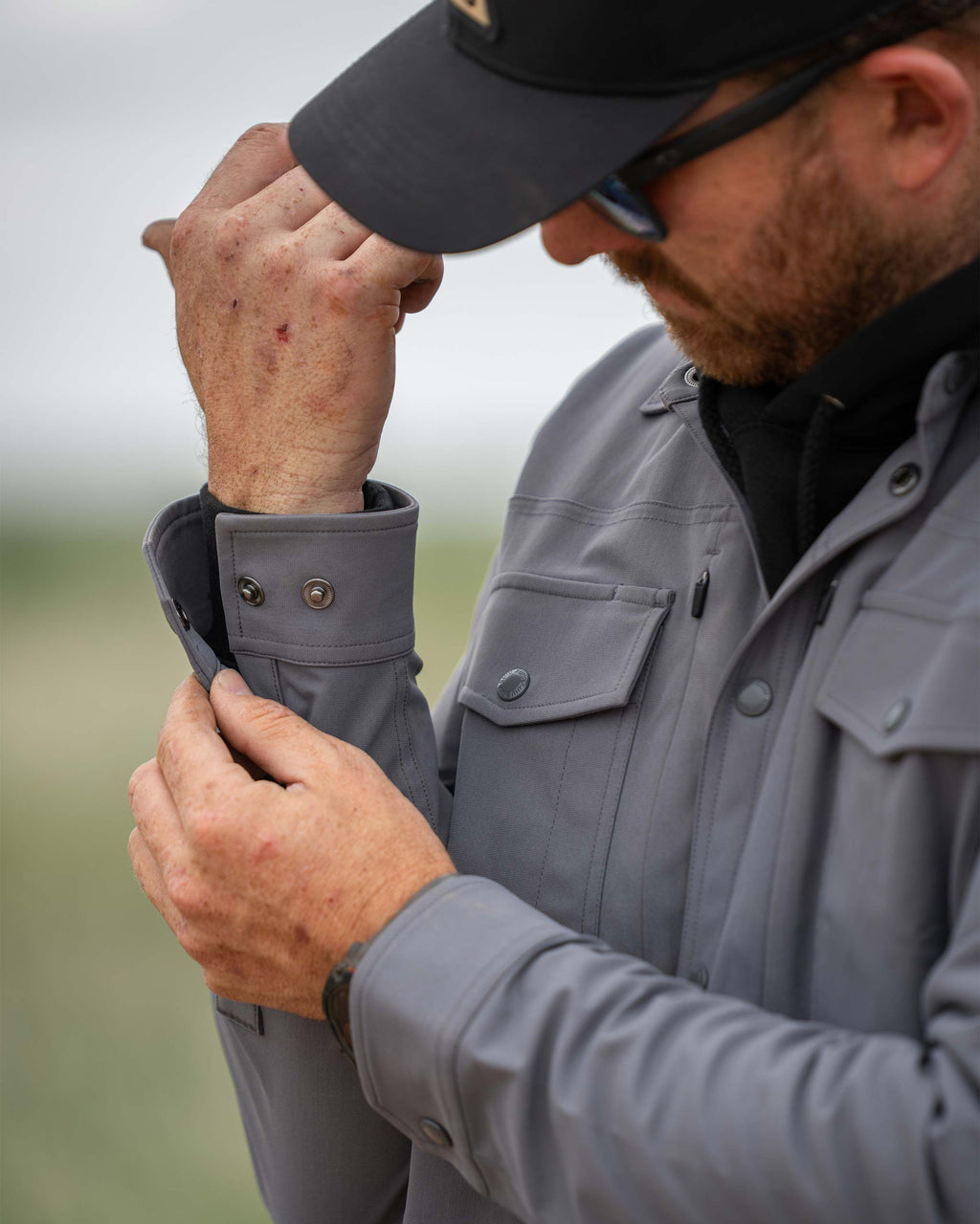 Man showcasing the snap closure buttons on the right cuff of the Tour Shirt Jacket in Castle Rock Grey