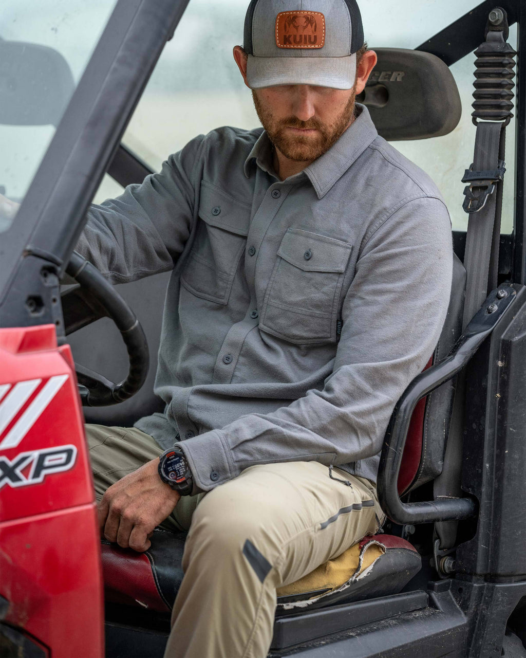 Man sits inside a Polaris Ranger XP vehicle, wearing Field Flnnel Shirt in Baltic Grey
