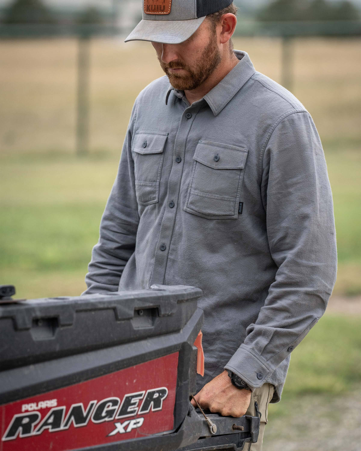 Man standing in the back of a Polaris Ranger XP vehicle while wearing Field Flannel Shirt in Baltic Grey