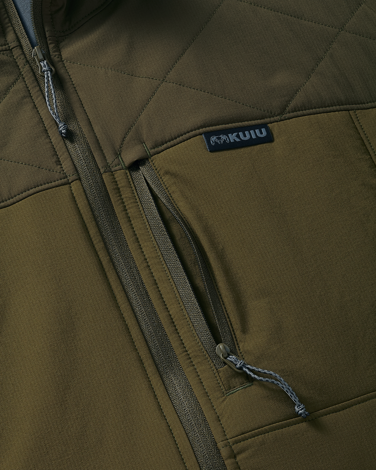 Close-up of an Transit Packable Hooded Jacket in Dark Army/Army with a vertical zippered pocket and a visible KUIU brand sewn-in label.