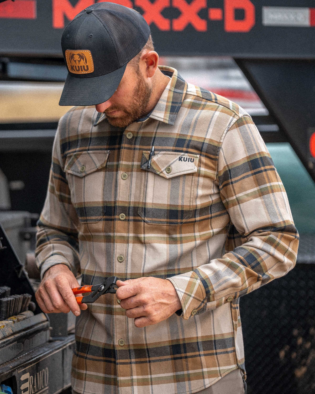 Man wearing Flannel Heavyweight in Valo Check Plaid holding a small wrench in his hand