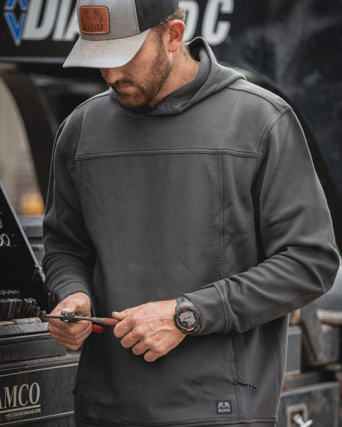 Man wearing Workgrade Utility Hoodie in Asphalt Grey holding a pair of pliers in his hand