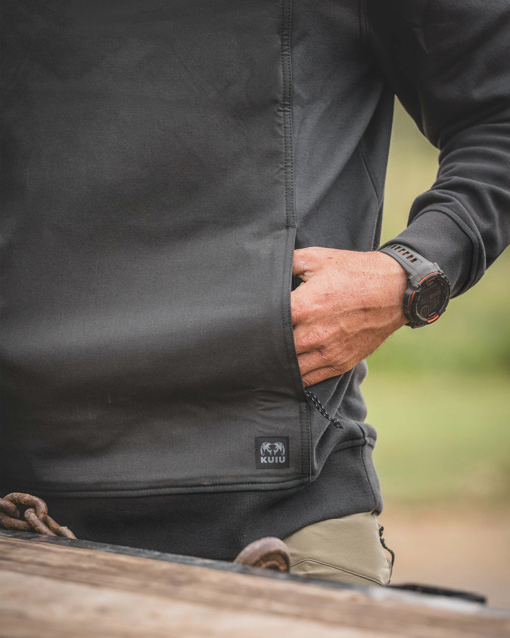 Close-up of a man placing his left hand inside the front pocket of a Workgrade Utility Hoodie in Asphalt Grey