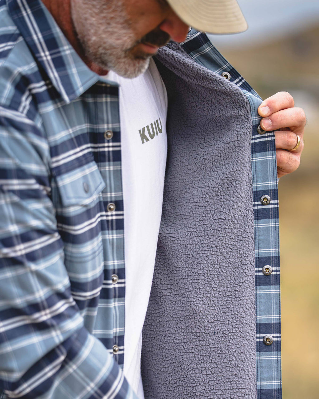 A close-up of a man wearing KUIU Field Flannel Fleece in Steel Blue Framework showing inner gray fleece lining.