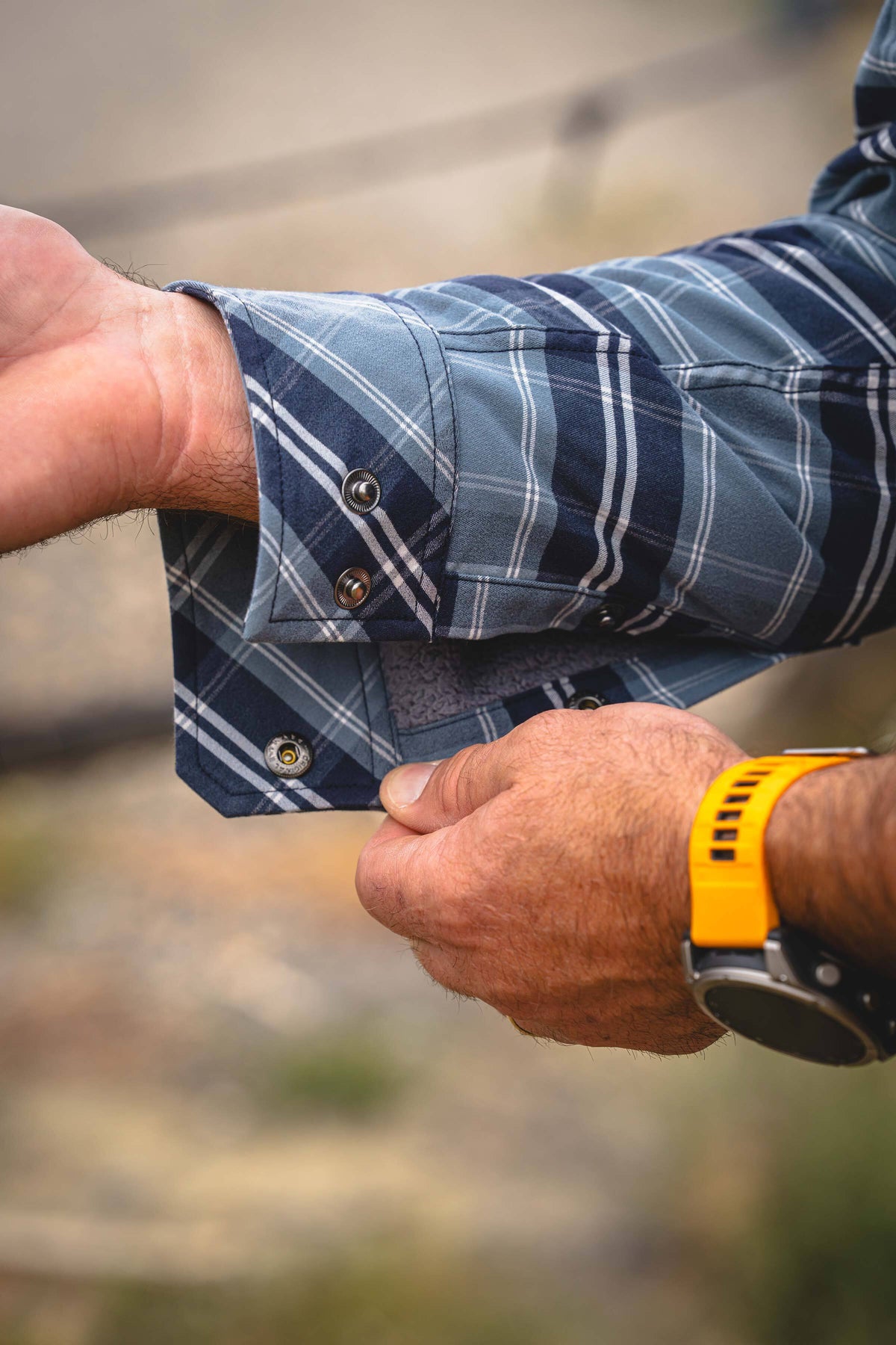 Close-up of a person's hands adjusting the cuff of a Field Flannel Fleece in Steel Blue Framework.