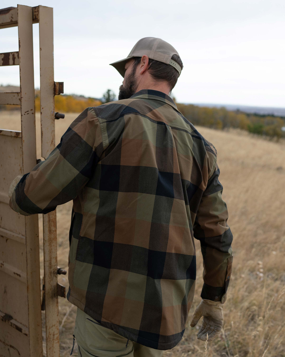 Hunter carefully opening the door on the cattle trailer, wearing Field Flannel Shirt Jacket in Valo Plaid