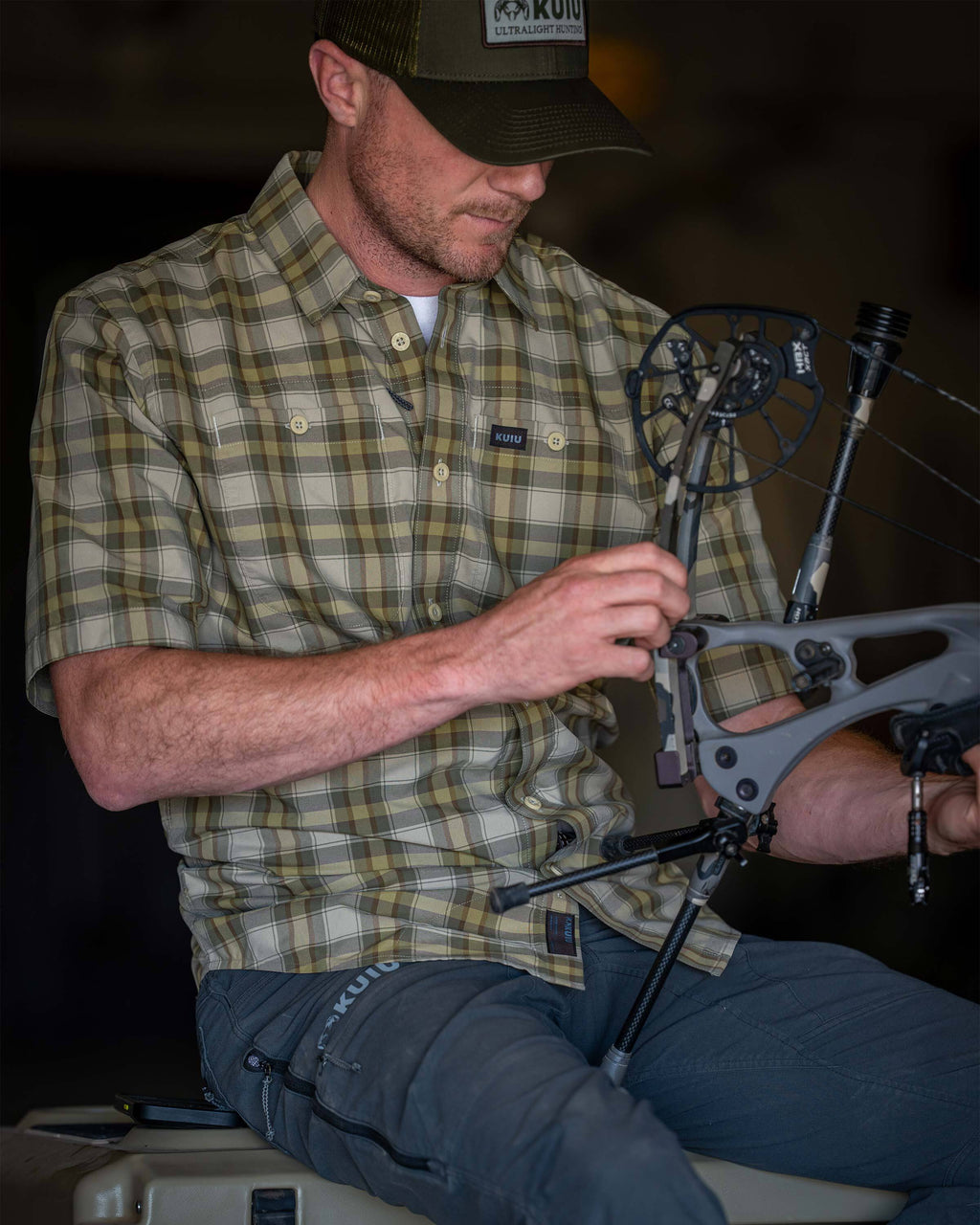 Man wearing Borrego Short Sleeve Shirt in Valo Crosscheck Plaid while adjusting a compound bow.
