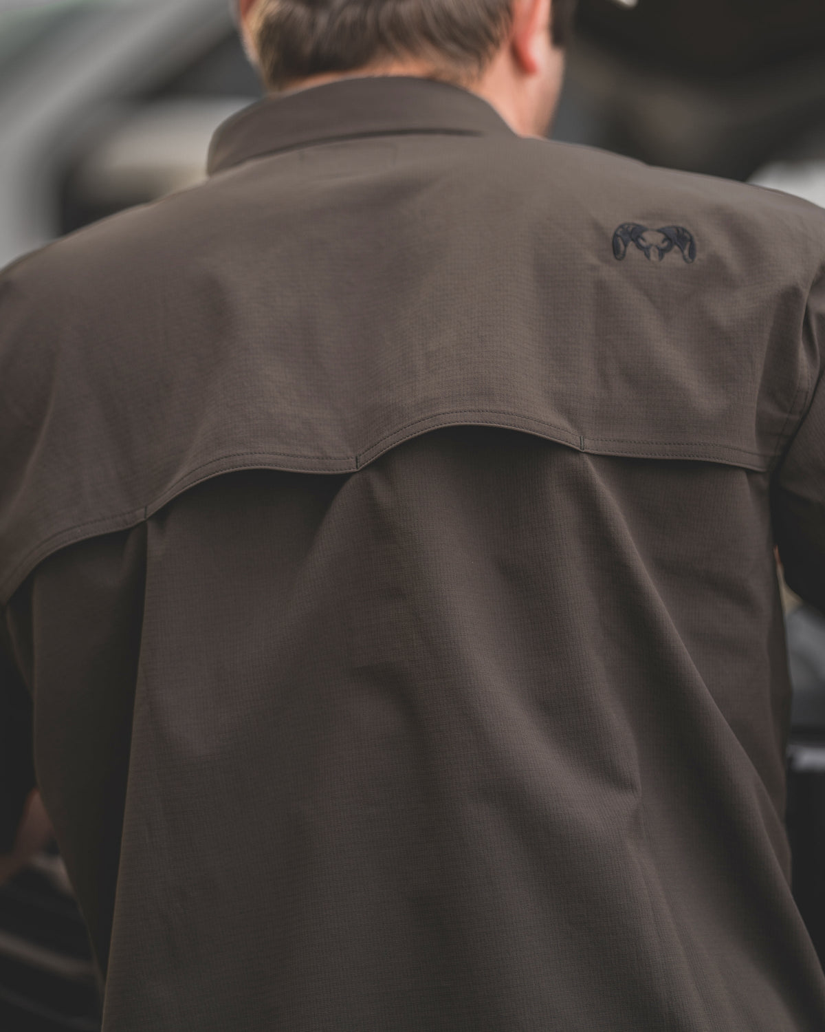 A detailed close-up of the back yoke on the Gauge Short Sleeve Work Shirt in Rodeo Brown, highlighting the integrated mesh-lined vent designed for enhanced breathability and airflow.