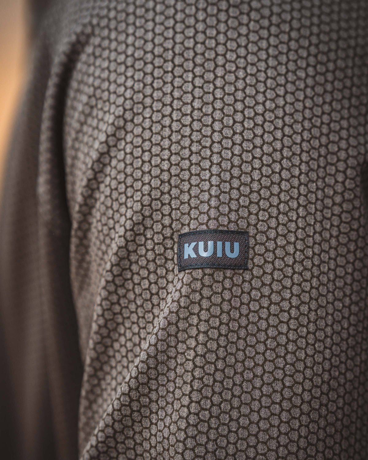 Close-up of Dura-knit Hoodie in Rodeo Brown, highlighting KUIU sewn-in label on left arm.