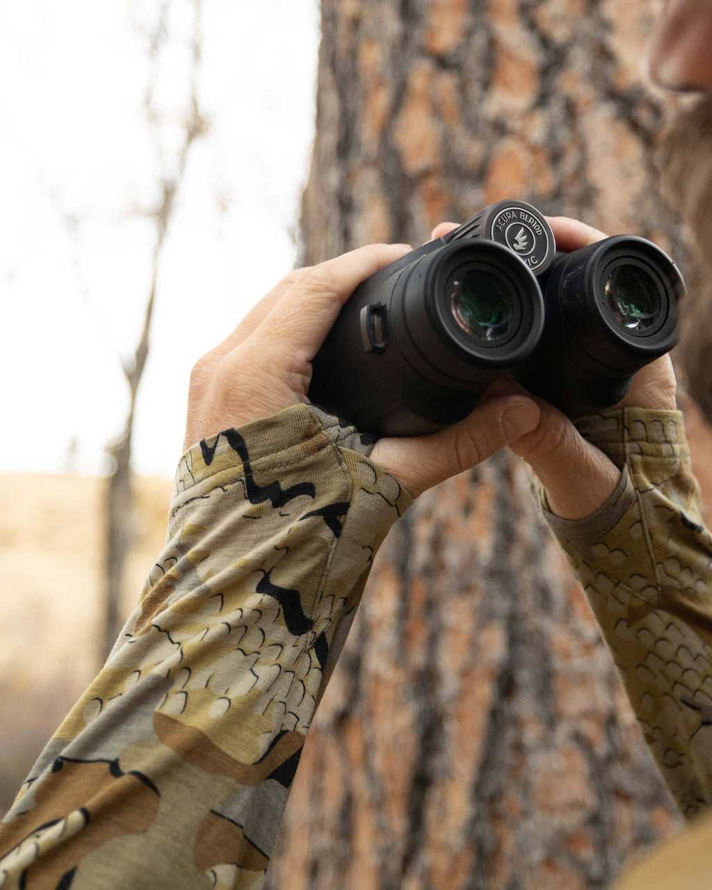 Close-up of Hunter holding a binocular, Highlighting thumbholes on the sleeves