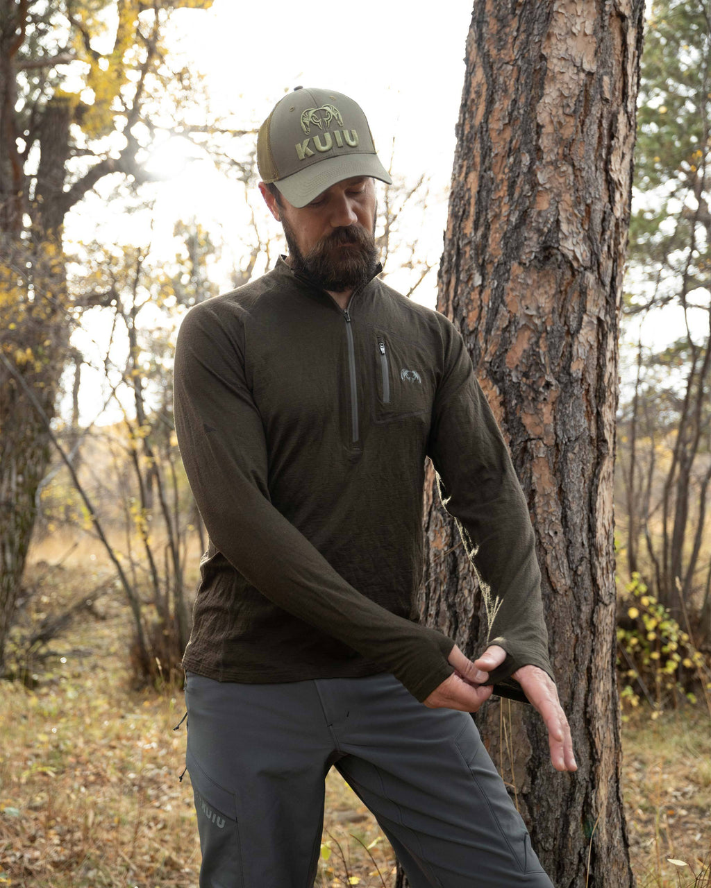Hunter adjusting his left sleeve thumbhole on the Ultra Merino 145 Zip-T Hunting Shirt in Loden Green