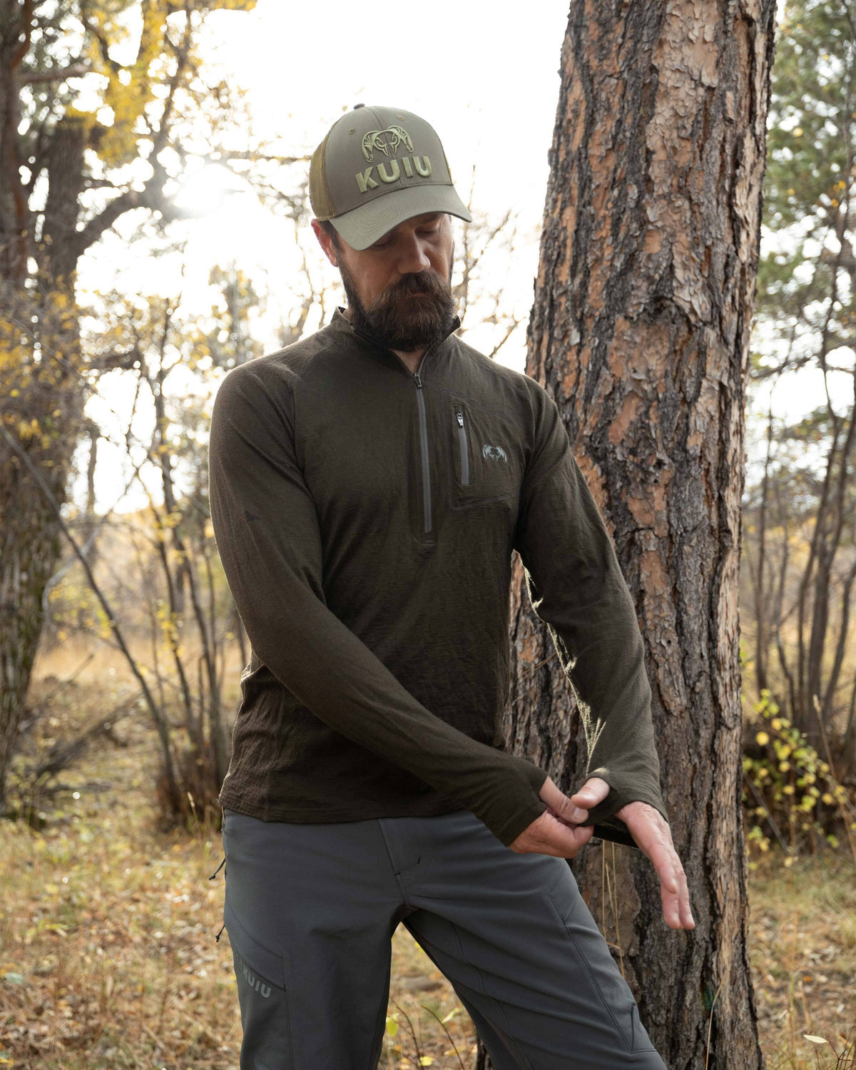 Hunter adjusting his left sleeve thumbhole on the Ultra Merino 145 Zip-T Hunting Shirt in Loden Green