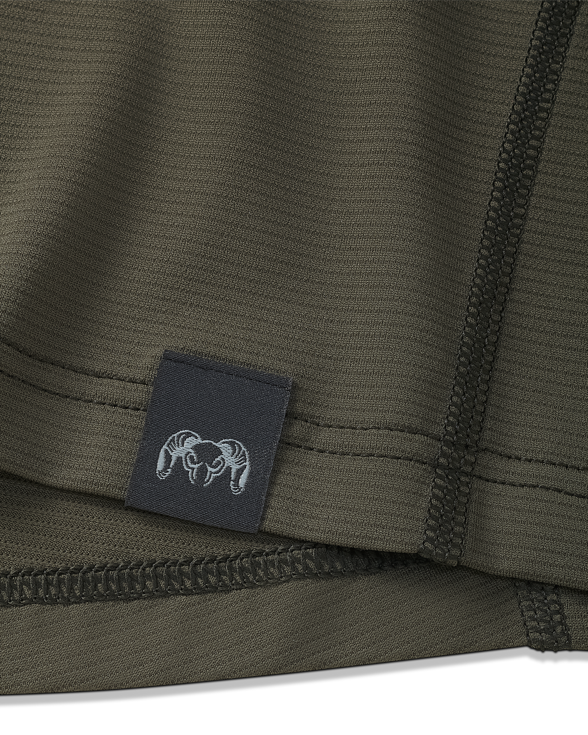 Close-up view of bottom seam of Vital S1 Short Sleeve in Ash Brown, Displaying a sewn in KUIU Ram logo on sewn-in tag 