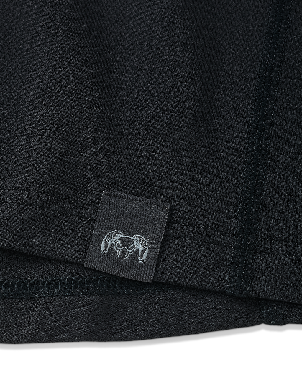 Close-up view of bottom seam of Vital S1 Short Sleeve in Black, Displaying a sewn in KUIU Ram logo on sewn-in tag 