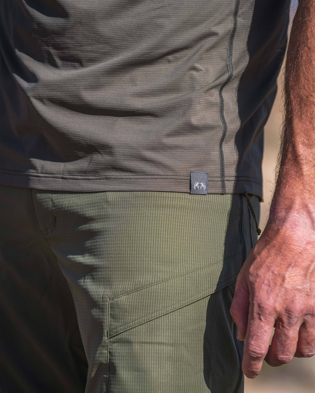 Close‑up view of Vital S1 Short Sleeve Crew, focusing on the lower torso at the hem, displaying a small KUIU Ram woven label.