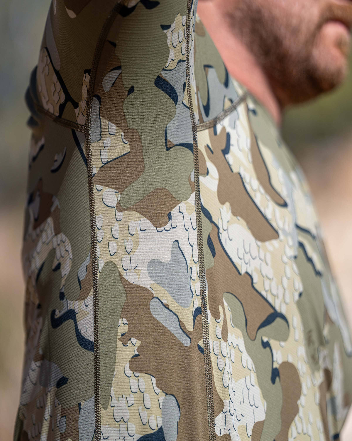 Close‑up view highlighting the upper torso and under arm area of Vital S1 Long Sleeve Crew in Valo Camouflage. Displaying flatlock seams run vertically and diagonally along the shoulder and upper arm, emphasizing articulated construction and durability. 