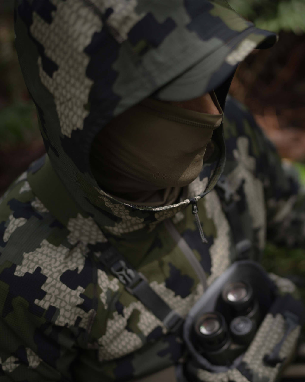 Hunter with a neck gaiter on, wearing Tiburon Hybrid Hoodie in Verde Camouflage