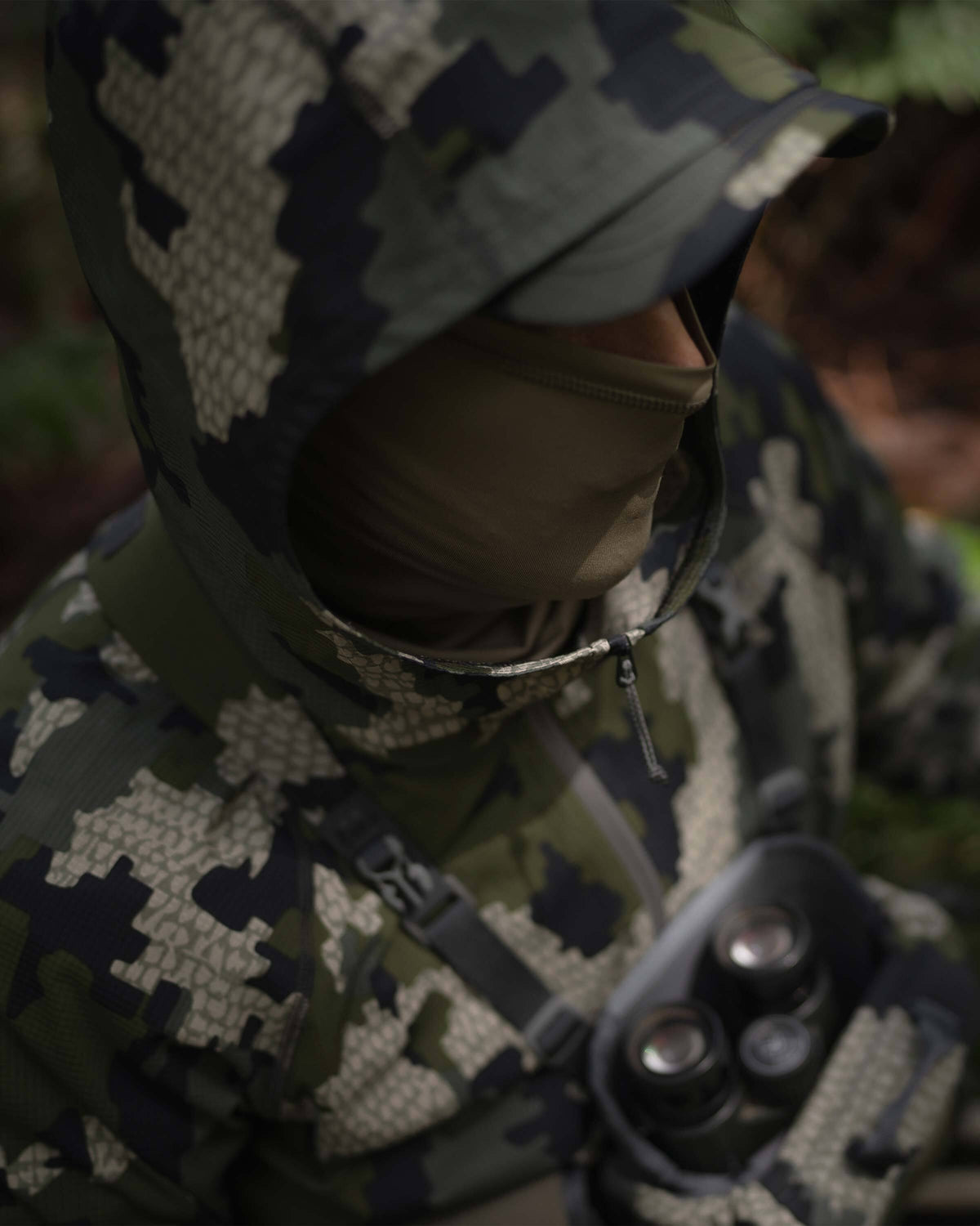 Hunter with a neck gaiter on, wearing Tiburon Hybrid Hoodie in Verde Camouflage