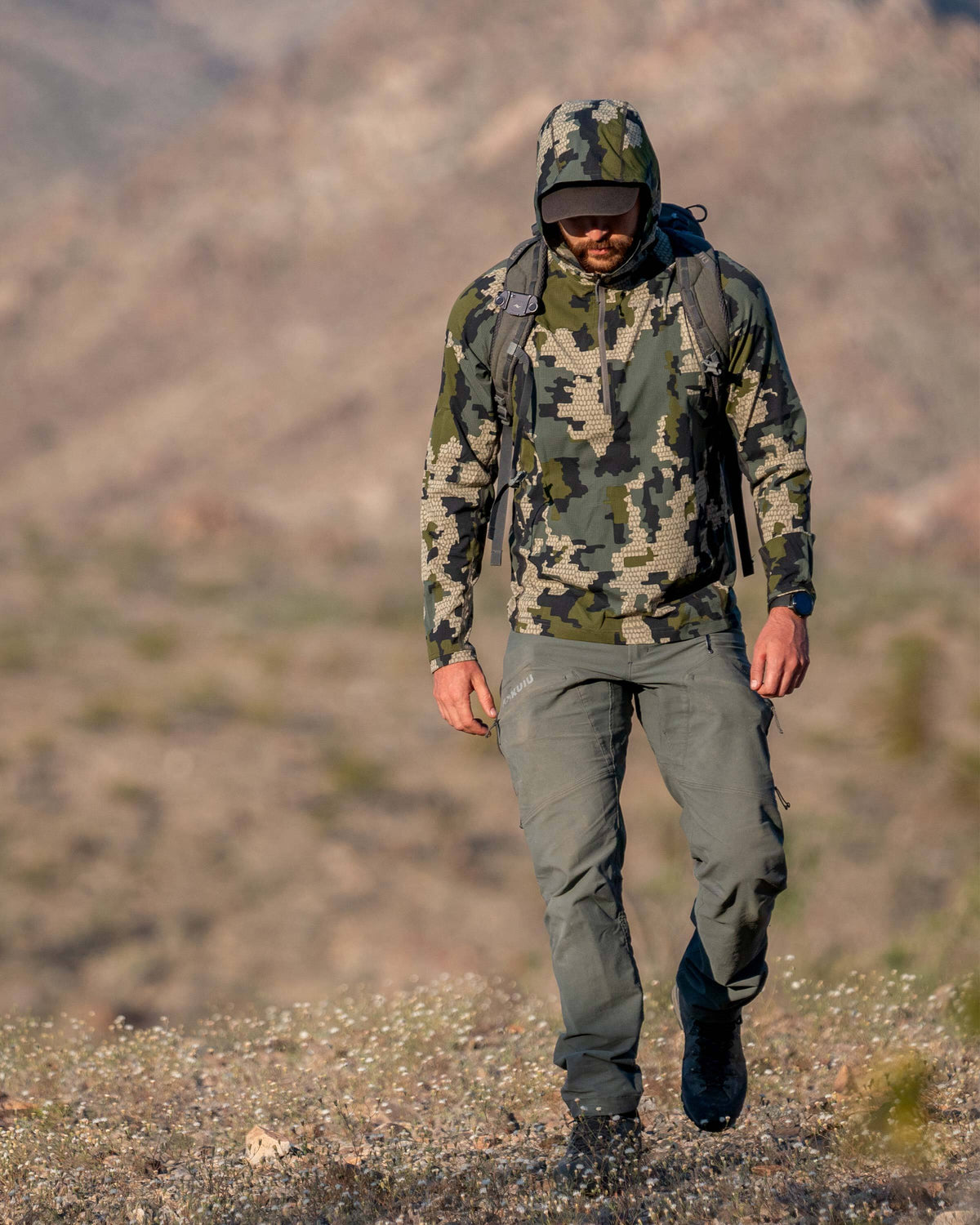 Hunter backpacking, hiking a desert terrain, wearing Tiburon Hybrid Hoodie Verde in Camouflage